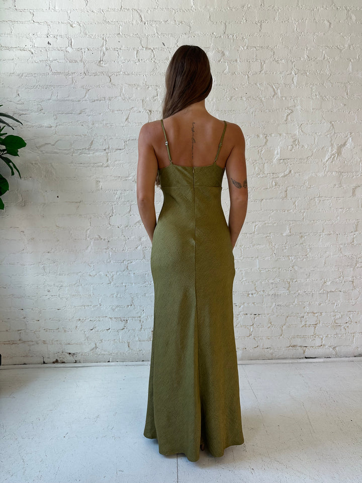 Woman wearing olive green textured maxi dress with v-neckline and adjustable spaghetti straps. 