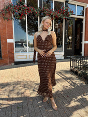 Woman wearing brown polka dot maxi dress with detachable neck scarf.