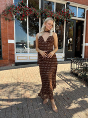 Woman wearing brown polka dot maxi dress with detachable neck scarf.