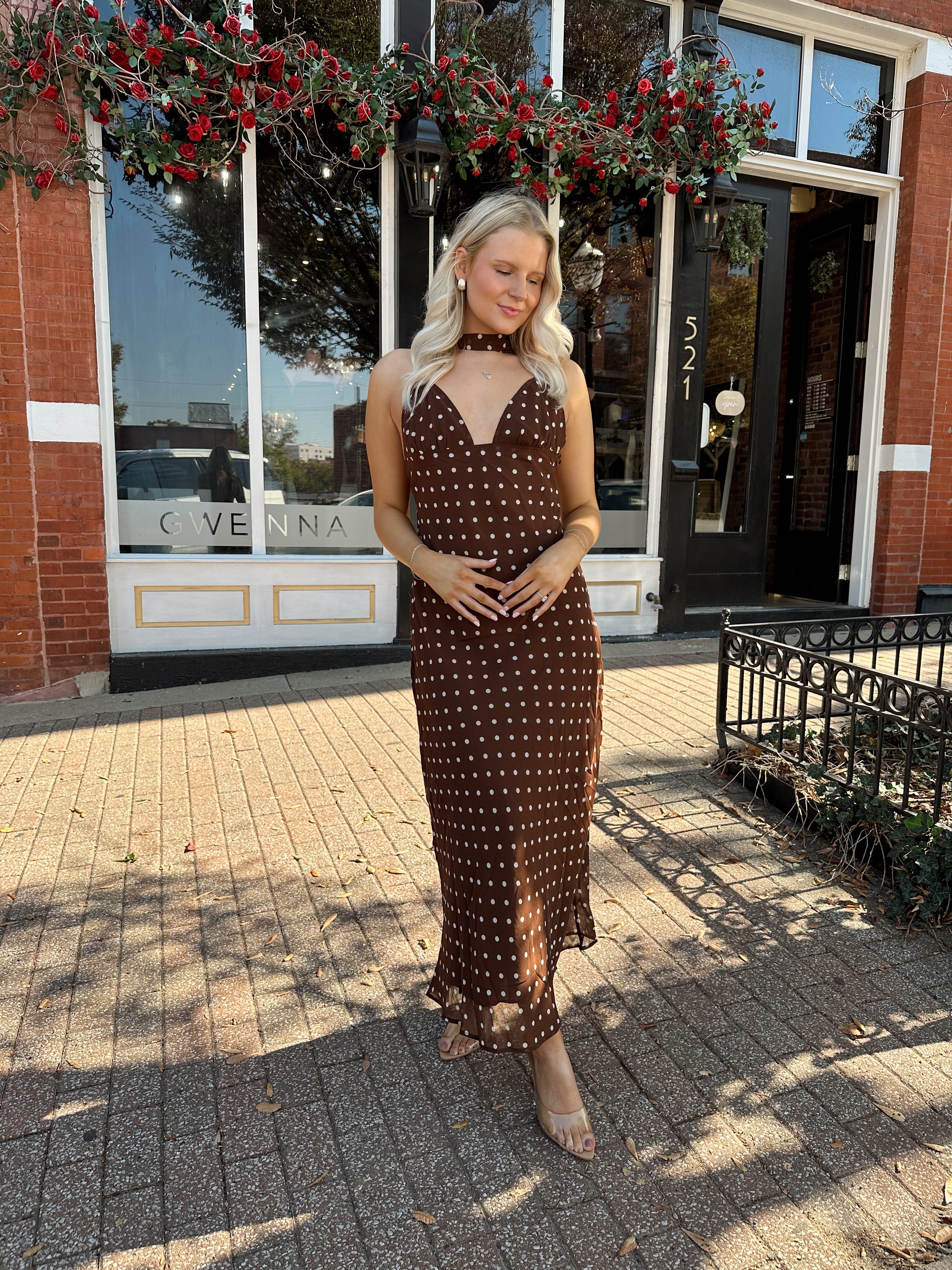 Woman wearing brown polka dot maxi dress with detachable neck scarf.