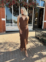 Woman wearing brown polka dot maxi dress with detachable neck scarf.