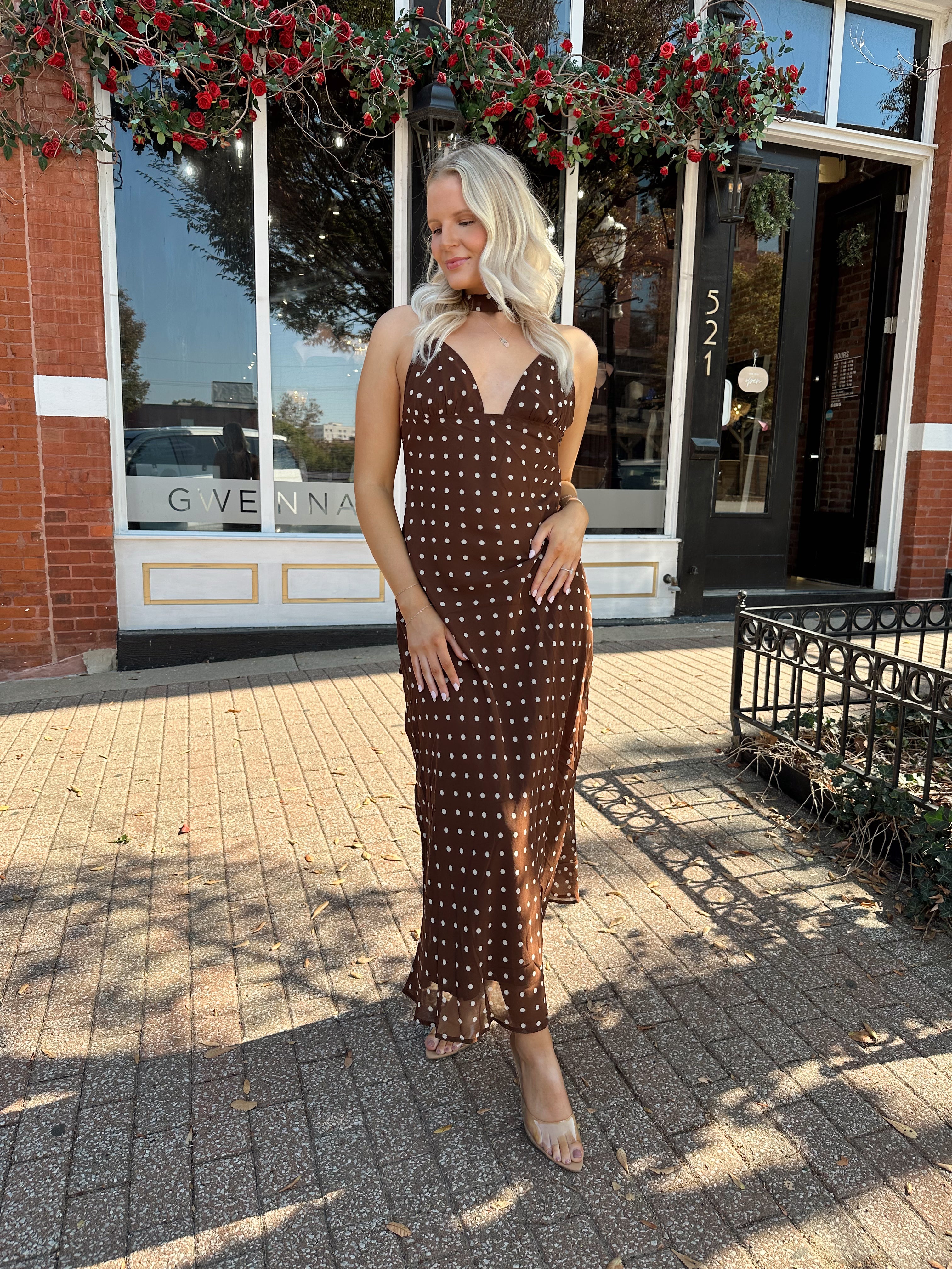 Woman wearing brown polka dot maxi dress with detachable neck scarf.