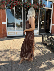 Woman wearing brown polka dot maxi dress with detachable neck scarf.