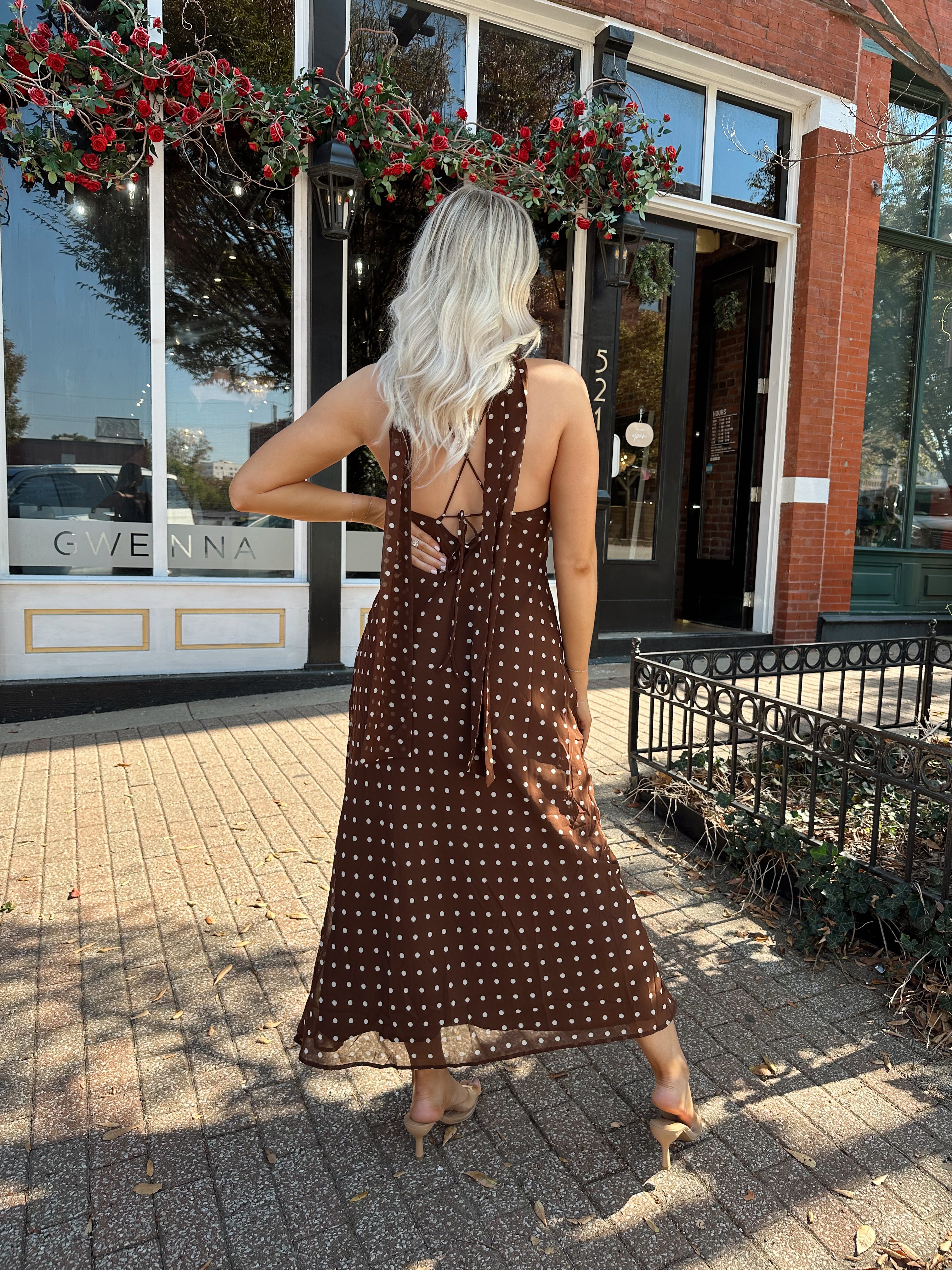 Woman wearing brown polka dot maxi dress with detachable neck scarf.