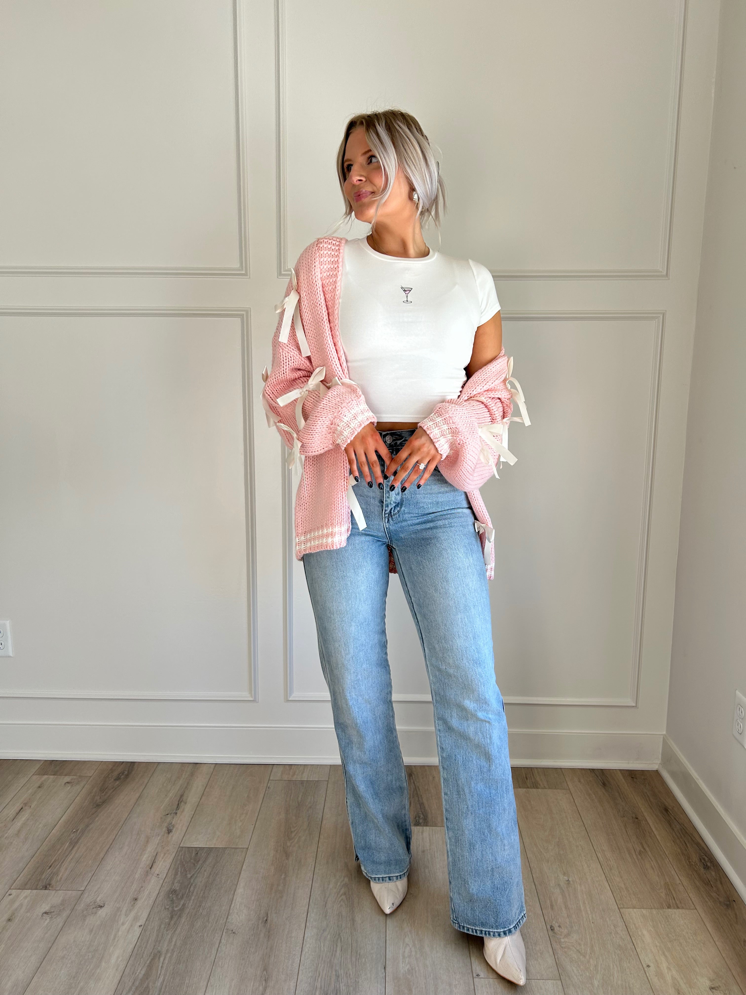 Pink knit cardigan with satin ribbon details and oversized cozy design.