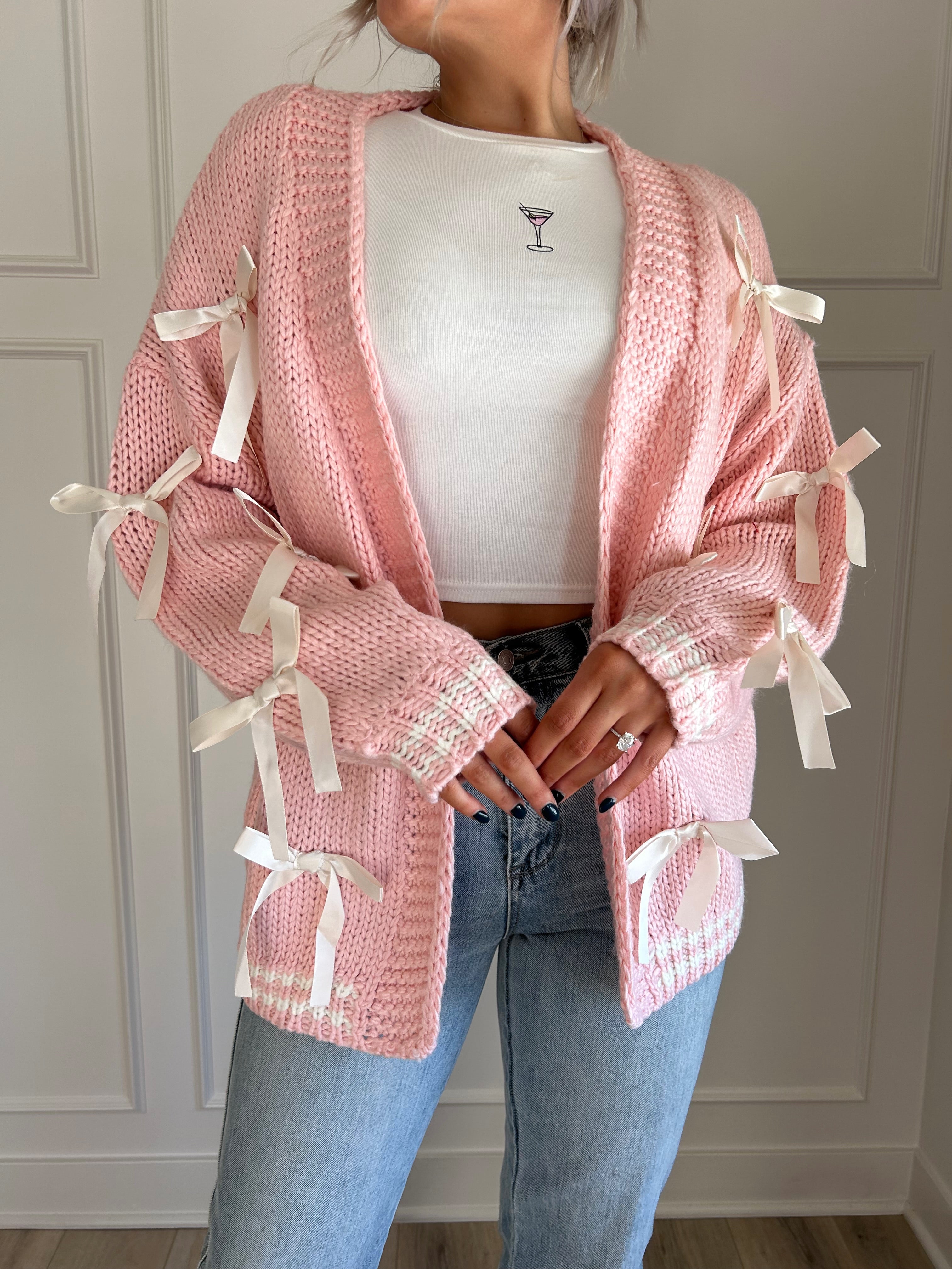 Pink knit cardigan with satin ribbon details and oversized cozy design.