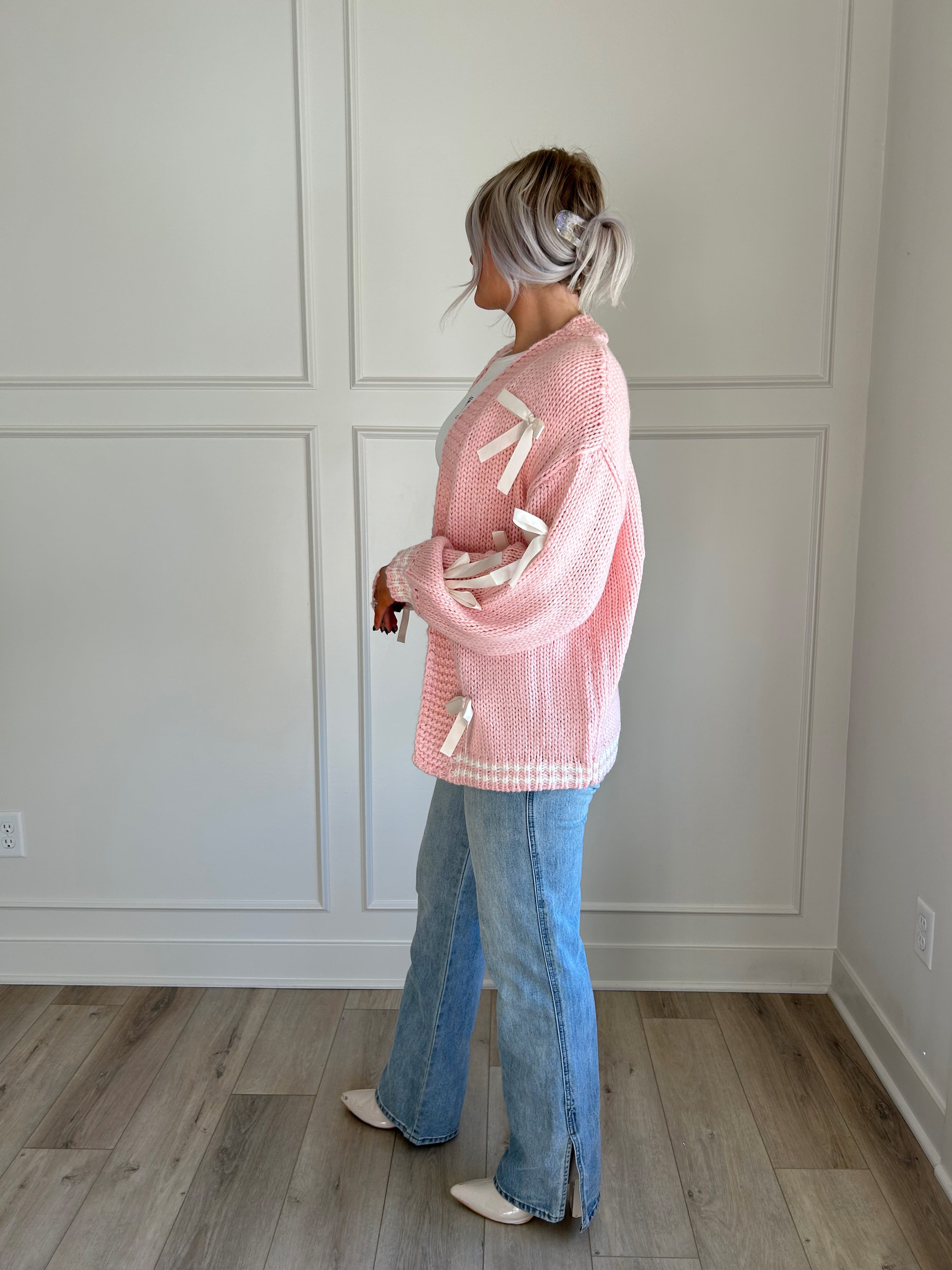 Pink knit cardigan with satin ribbon details and oversized cozy design.