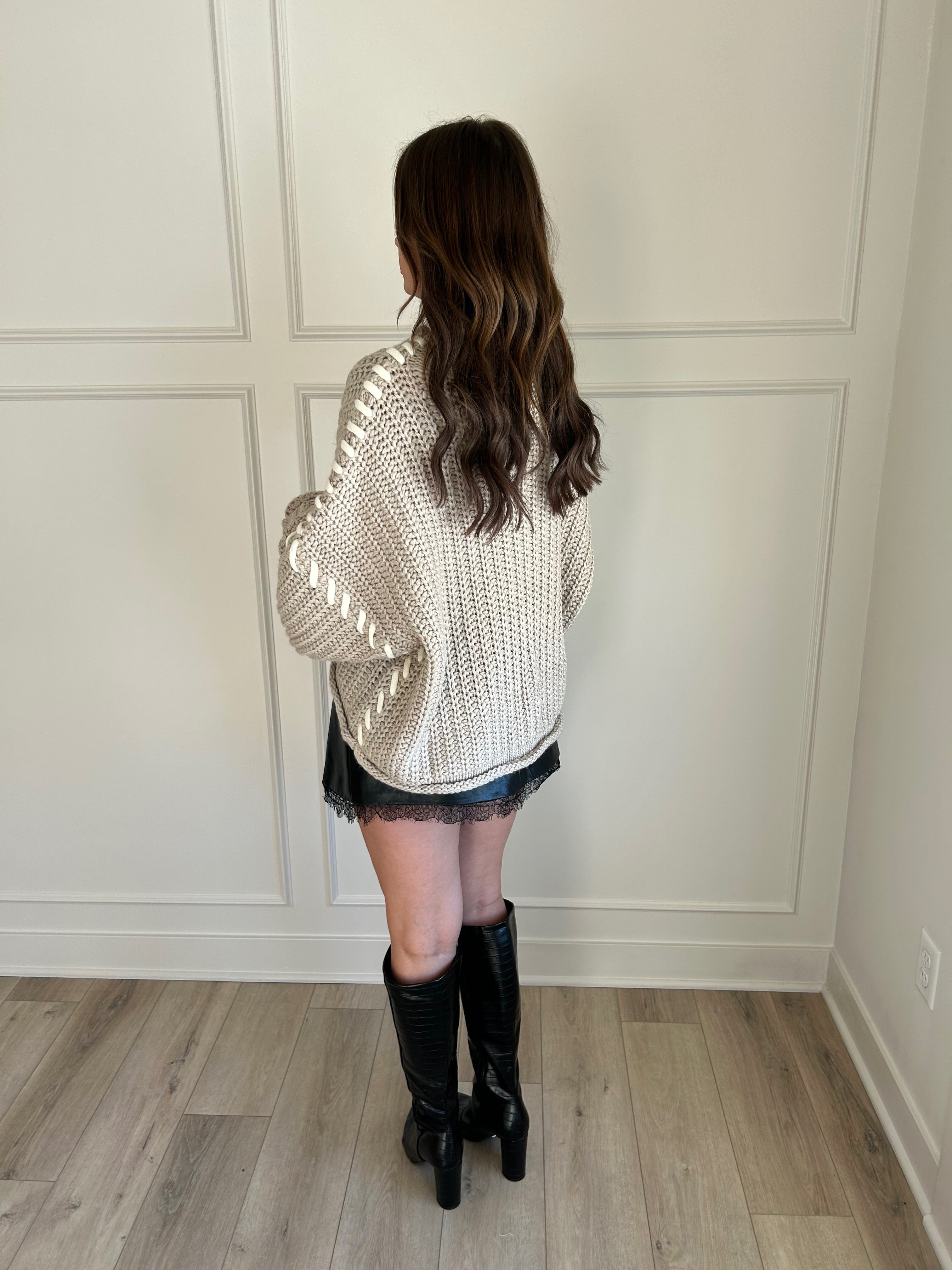 Beige chunky knit sweater with lace-up sleeve details and cozy fit.