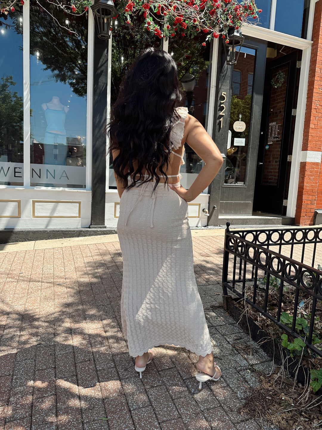 Woman wearing tan crochet midi dress with open back and self tie closure. 