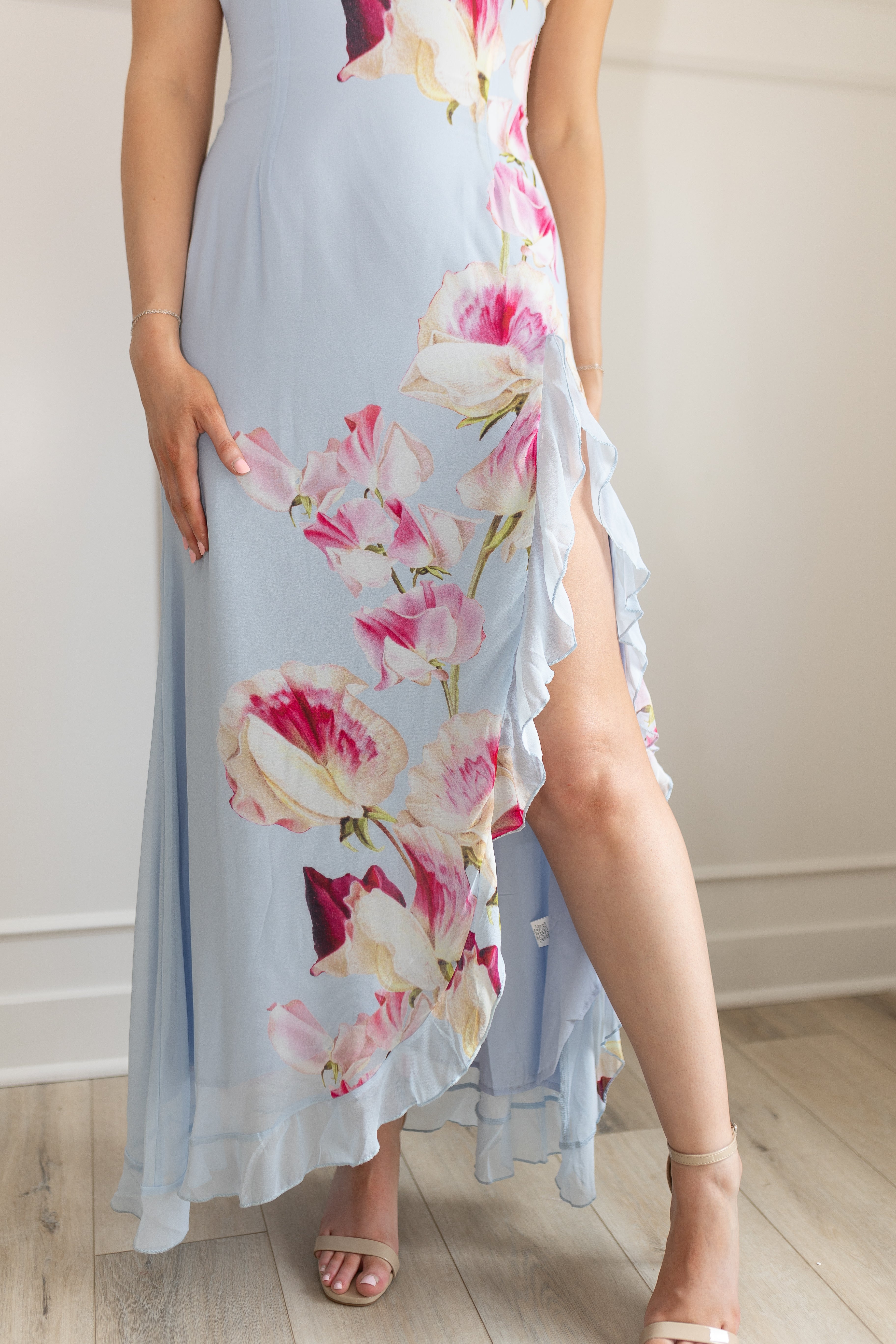 Blue maxi dress with pink floral pattern. Slit with a ruffle detail. 
