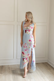Blue maxi dress with pink floral pattern. Slit with a ruffle detail. 