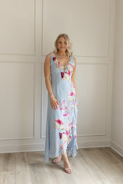 Blue maxi dress with pink floral pattern. Slit with a ruffle detail. 