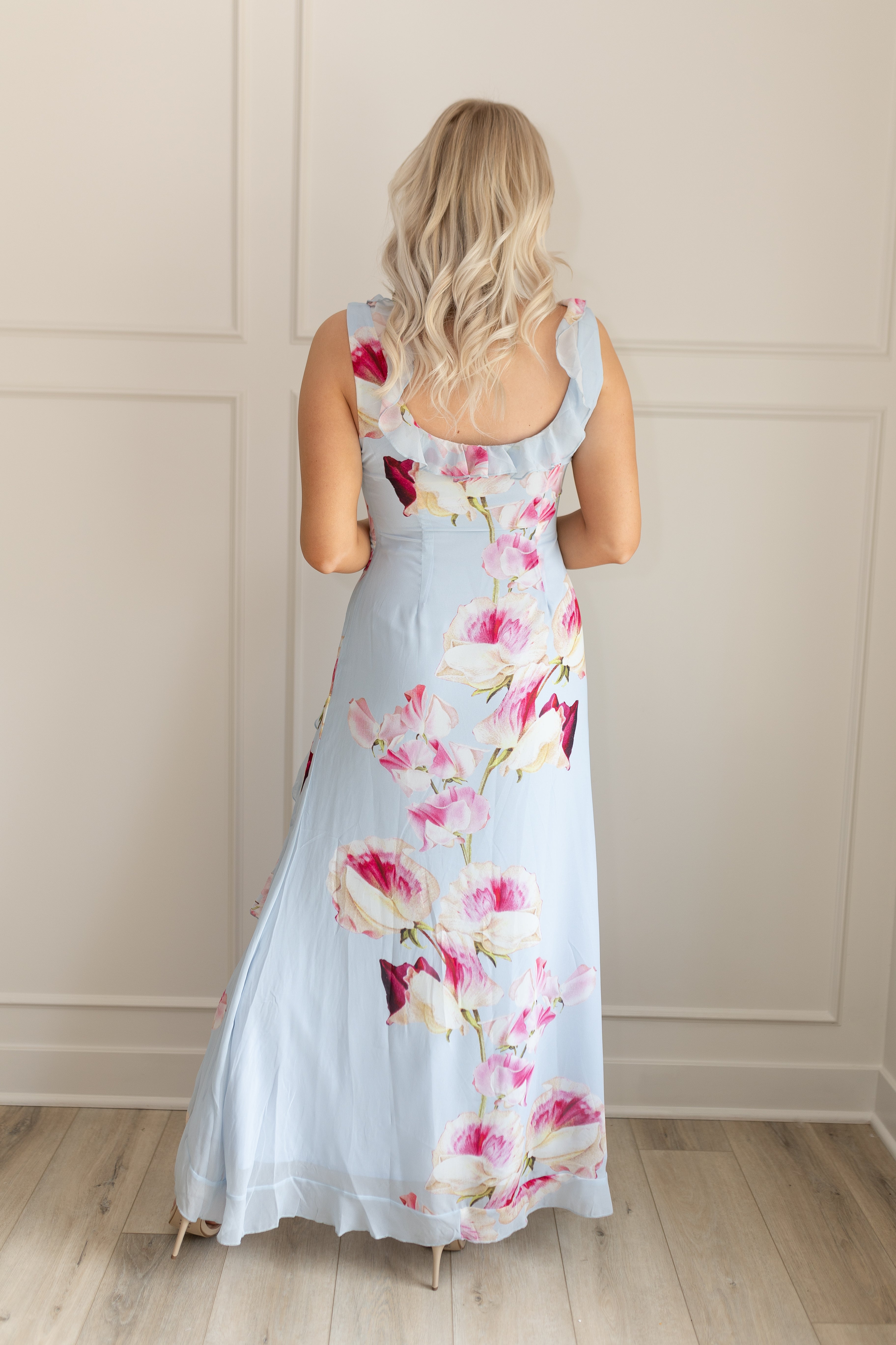 Blue maxi dress with pink floral pattern. Slit with a ruffle detail. 