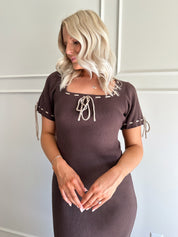 Woman wearing chocolate brown sweater midi dress with contrast trim and tie details.