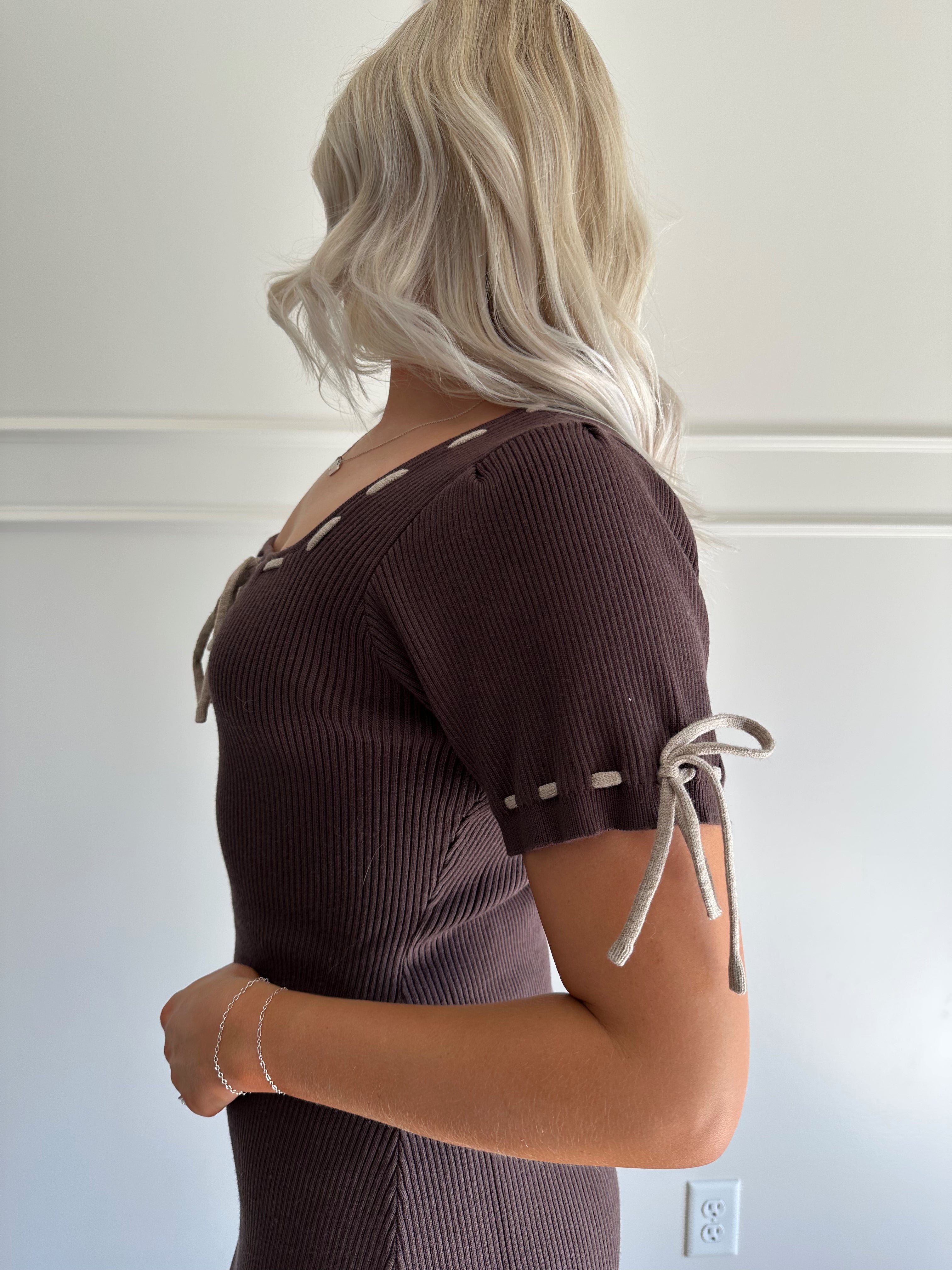 Woman wearing chocolate brown sweater midi dress with contrast trim and tie details.