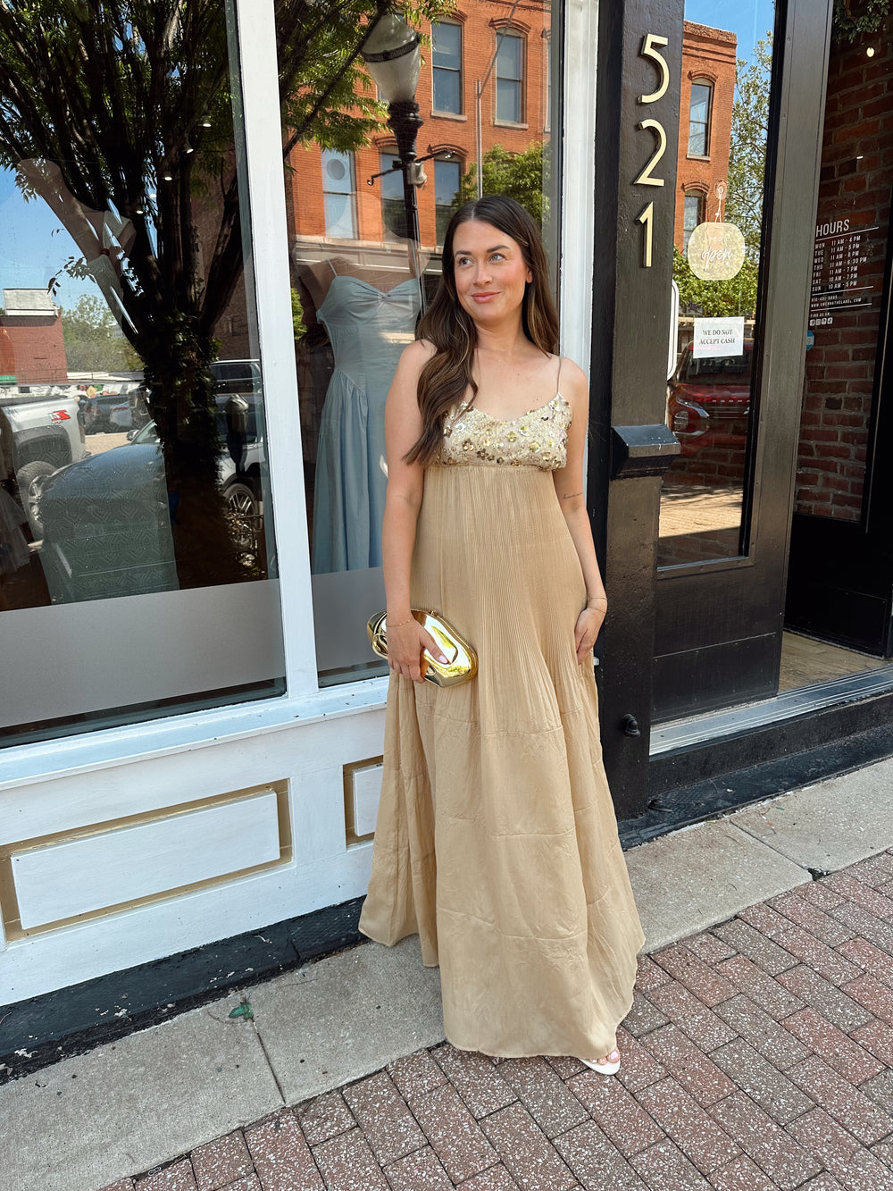 Woman wearing gold pleated maxi dress with sequin bust and adjustable spaghetti straps. 