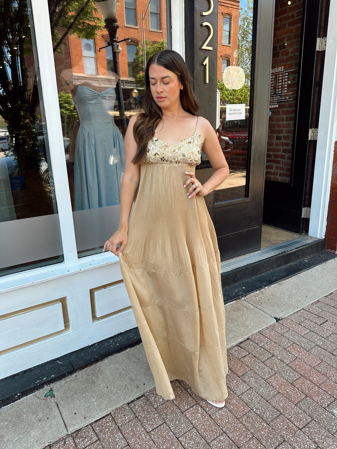 Woman wearing gold pleated maxi dress with sequin bust and adjustable spaghetti straps. 