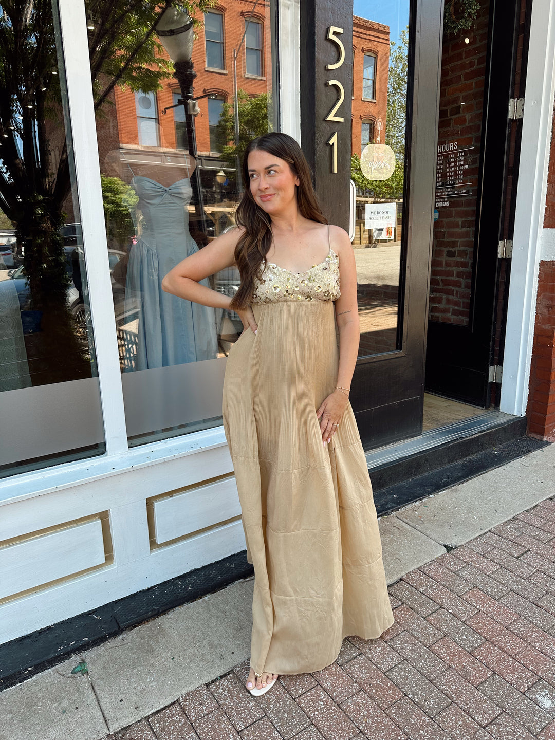 Woman wearing gold pleated maxi dress with sequin bust and adjustable spaghetti straps. 