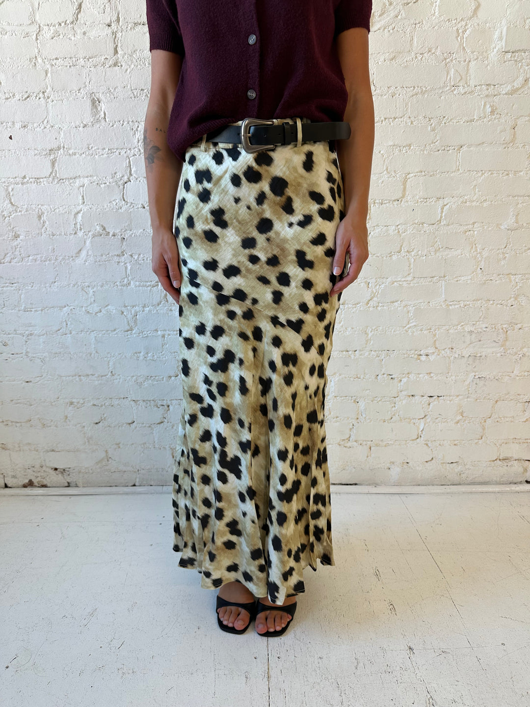 Woman wearing leopard satin belted maxi skirt with burgundy sweater top. 
