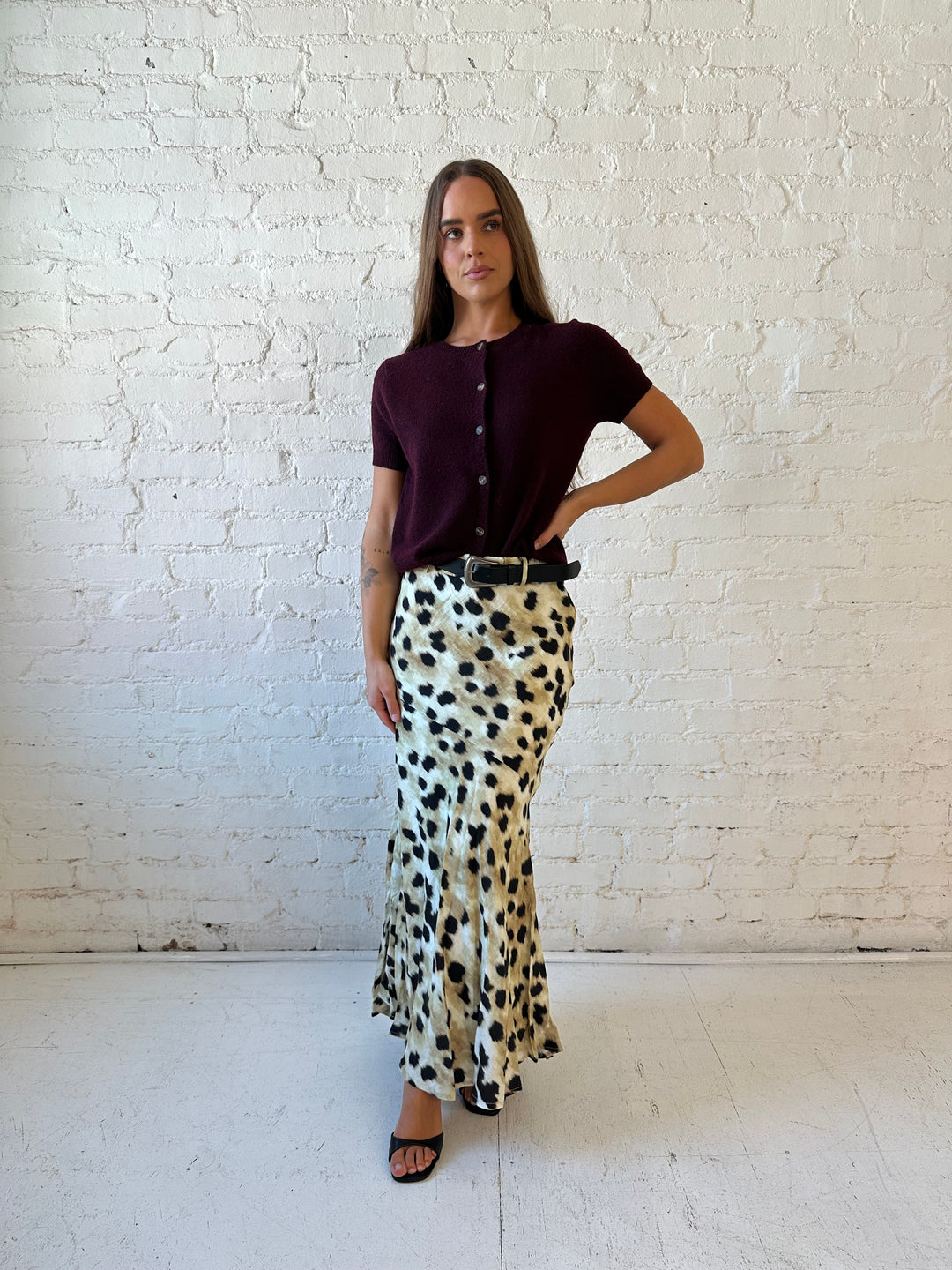 Woman wearing leopard satin belted maxi skirt with burgundy sweater top. 