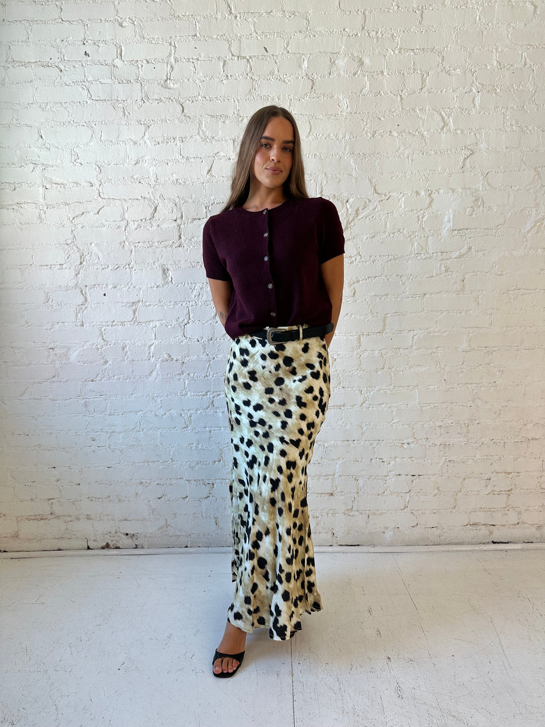 Woman wearing leopard satin belted maxi skirt with burgundy sweater top. 