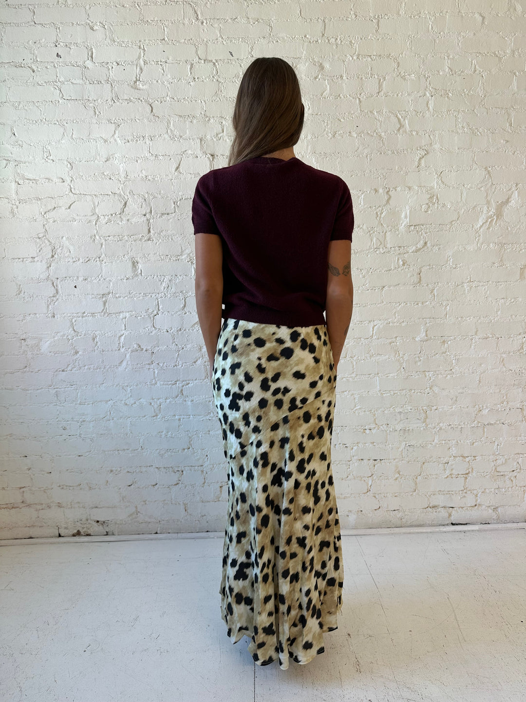 Woman wearing leopard satin belted maxi skirt with burgundy sweater top. 