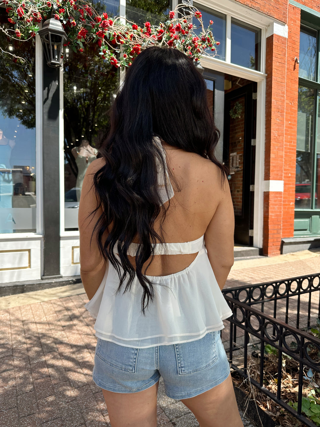 Woman wearing medium wash denim short with chiffon alter top.