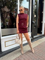 Woman wearing burgundy suede high neck mini dress with belted detail and functional pockets.