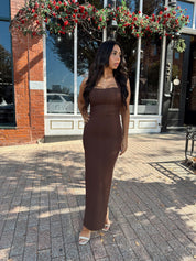 Woman wearing brown fitted square neck midi dress with slit in the back.