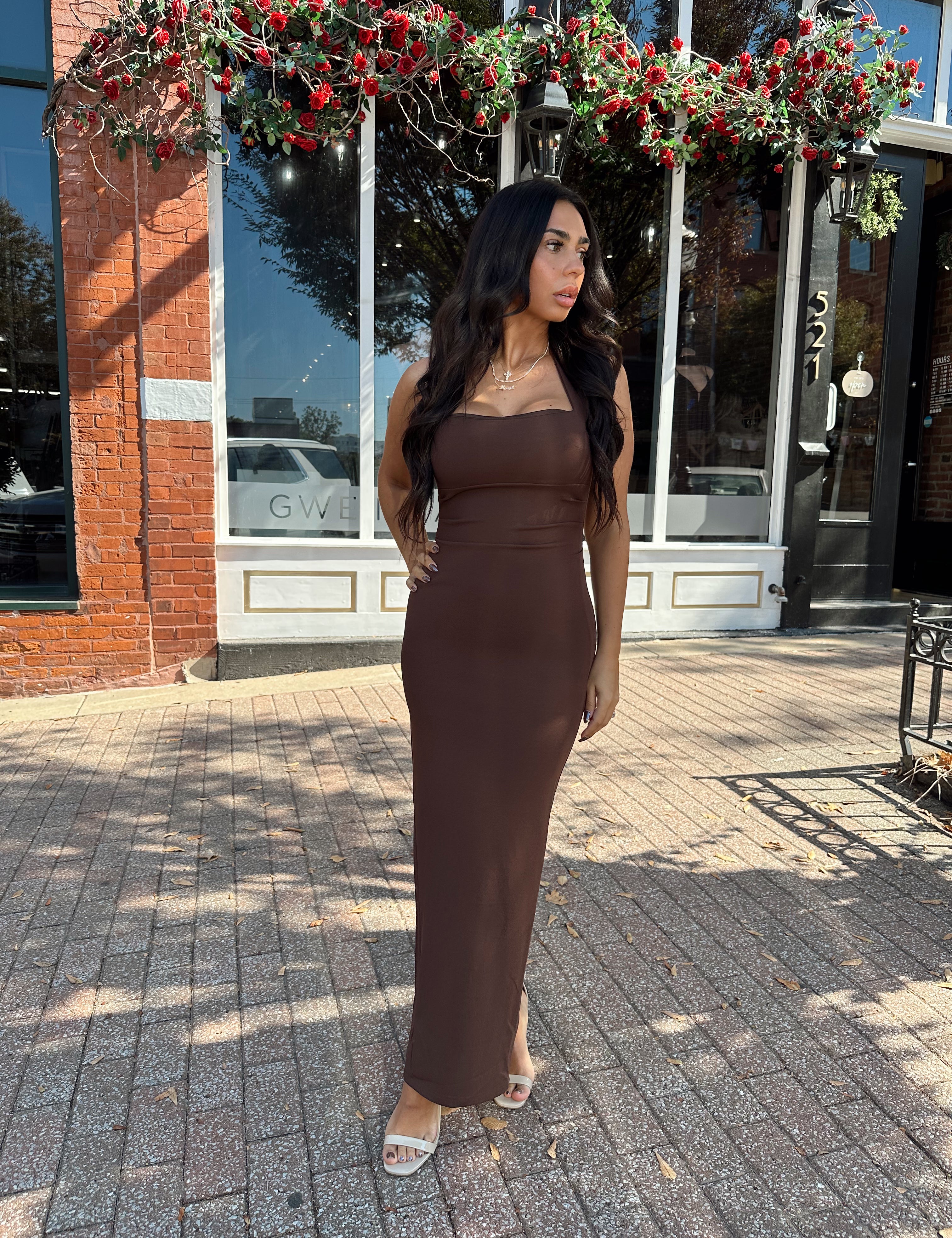 Woman wearing brown fitted square neck midi dress with slit in the back.