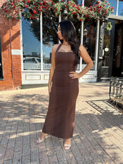 Woman wearing brown fitted square neck midi dress with slit in the back.