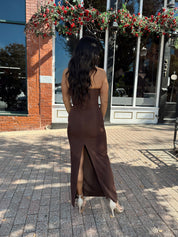 Woman wearing brown fitted square neck midi dress with slit in the back.