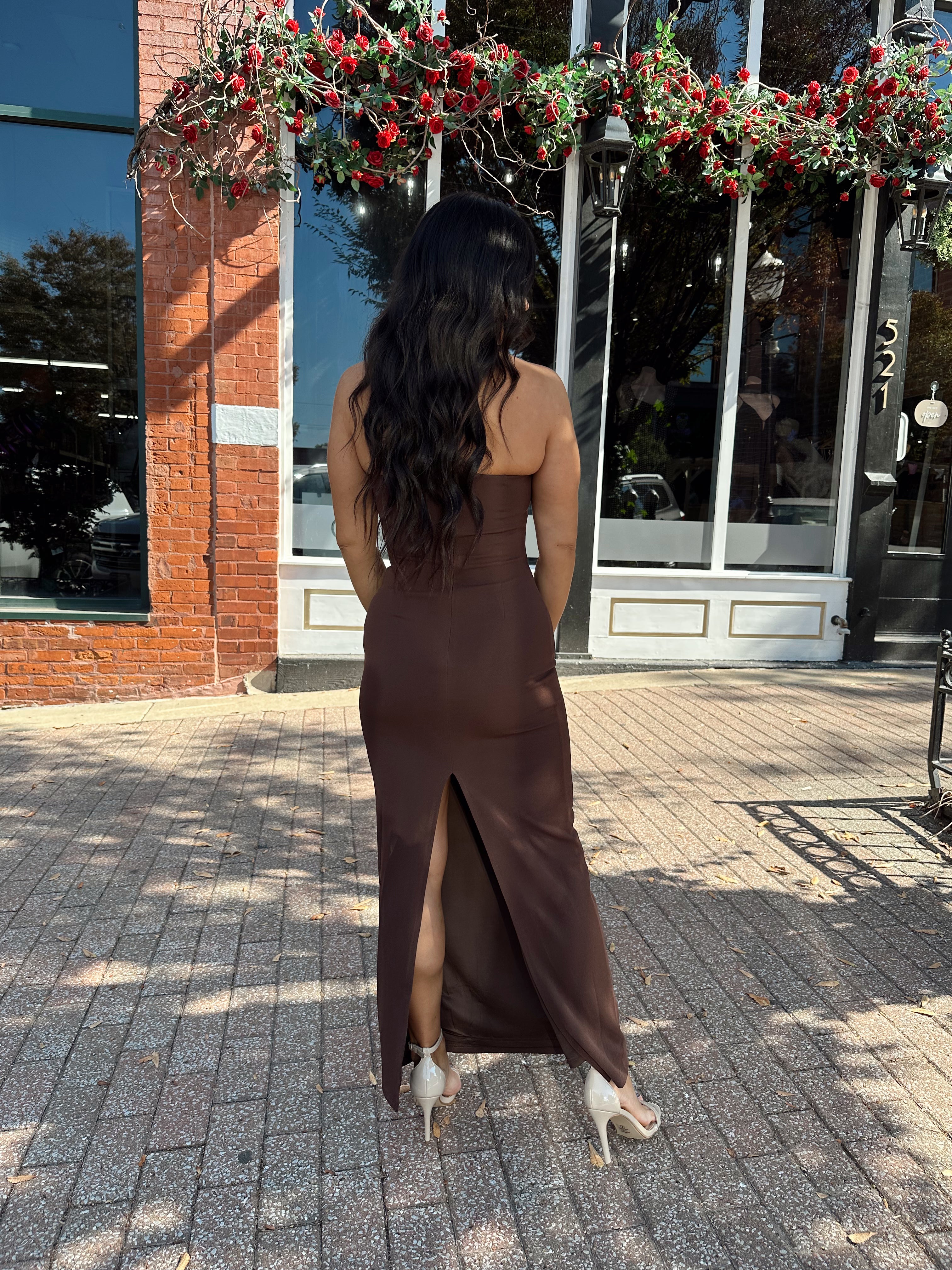 Woman wearing brown fitted square neck midi dress with slit in the back.