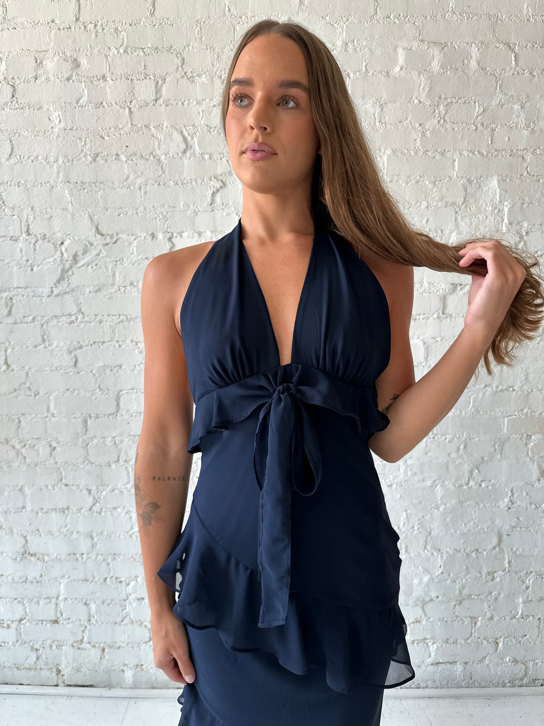 Woman wearing navy blue halter maxi dress with ruffle tiered detailing. 