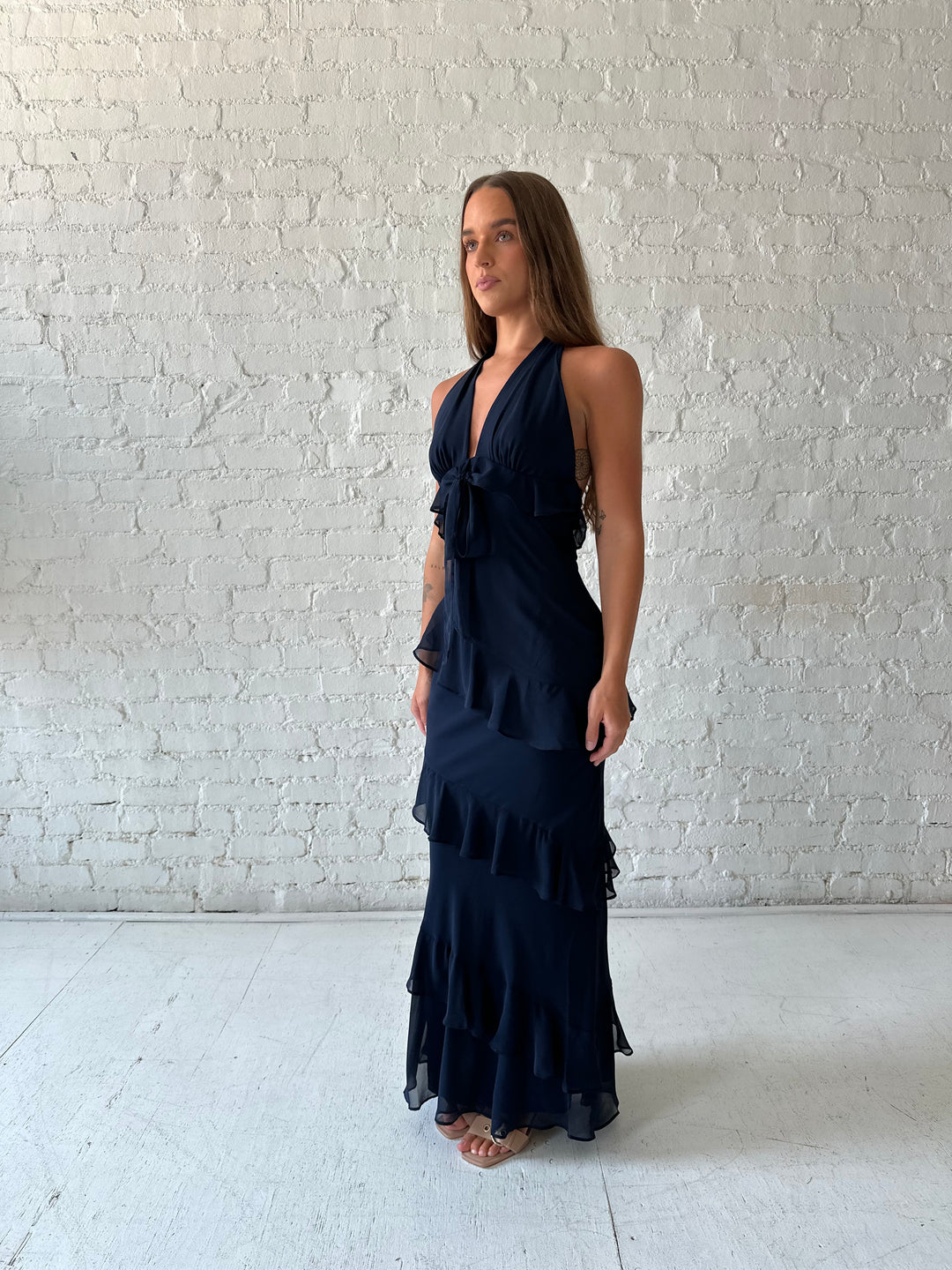 Woman wearing navy blue halter maxi dress with ruffle tiered detailing. 