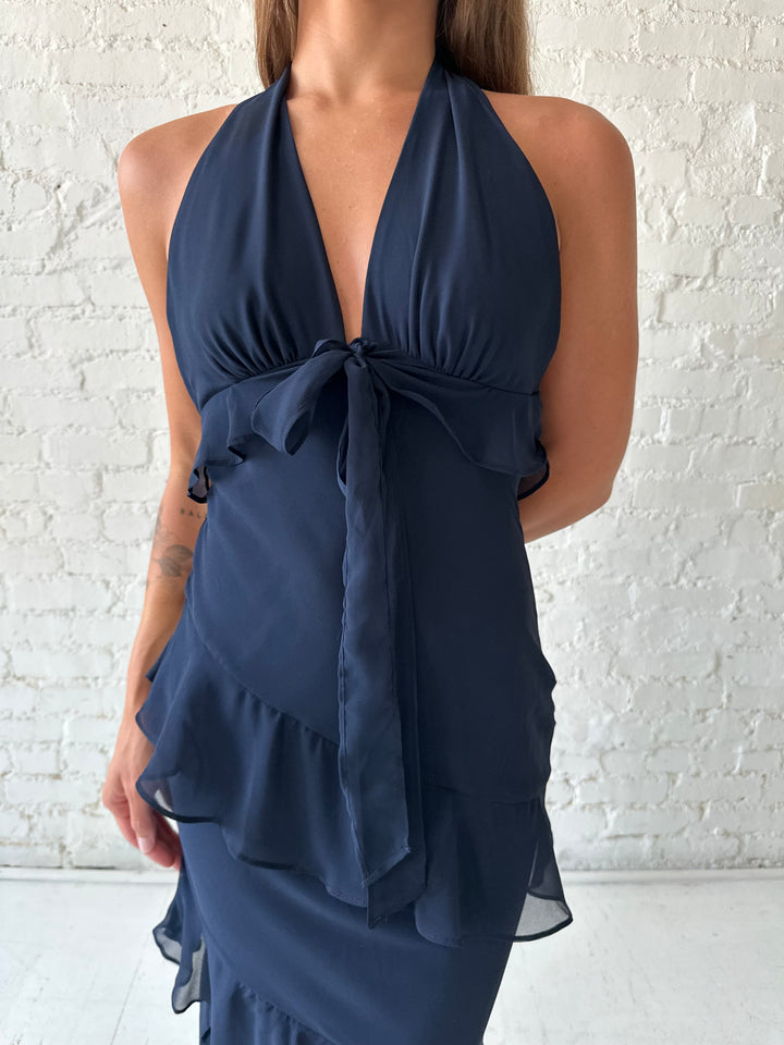 Woman wearing navy blue halter maxi dress with ruffle tiered detailing. 