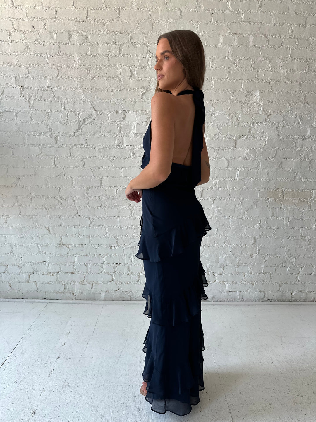 Woman wearing navy blue halter maxi dress with ruffle tiered detailing. 