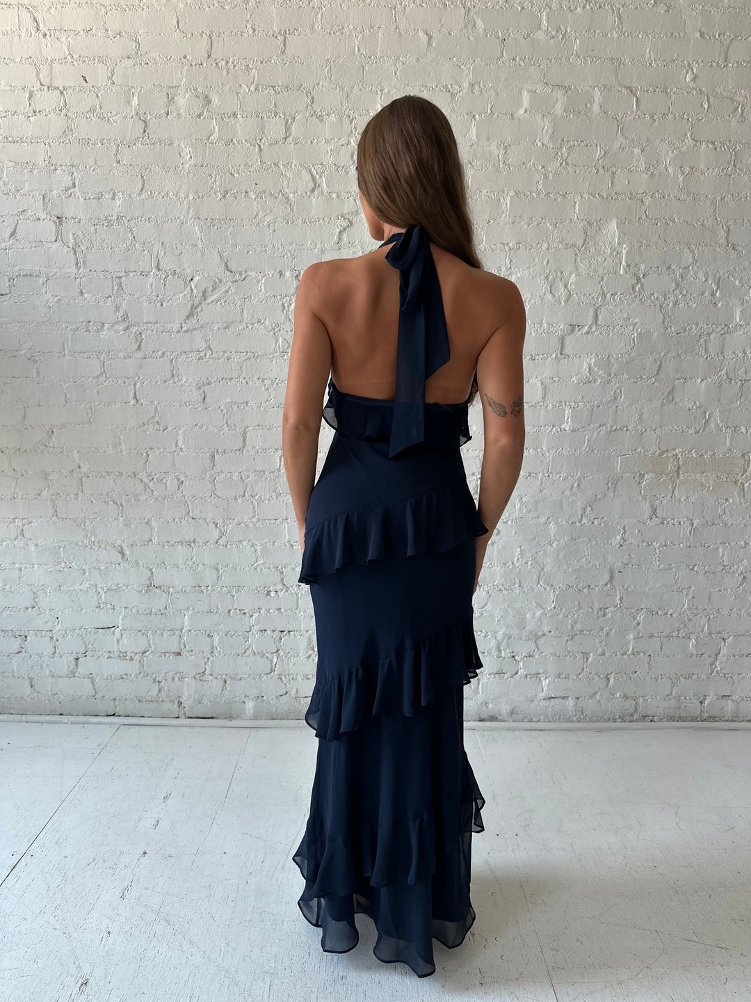 Woman wearing navy blue halter maxi dress with ruffle tiered detailing. 