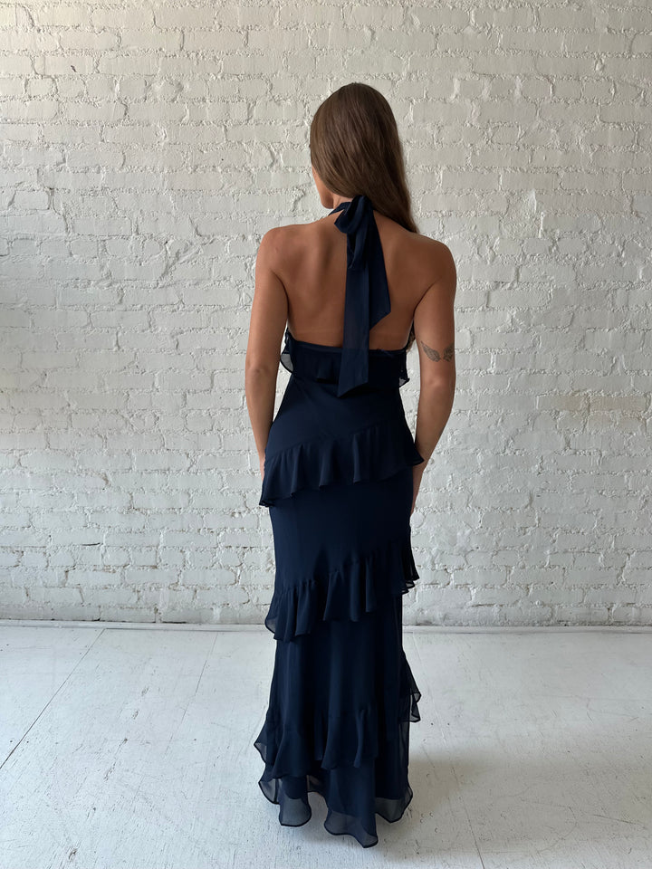 Woman wearing navy blue halter maxi dress with ruffle tiered detailing. 