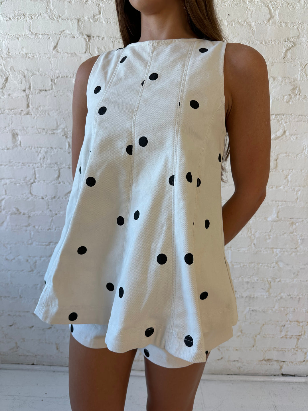 Woman wearing ivory polka dot set with black kitten heels.