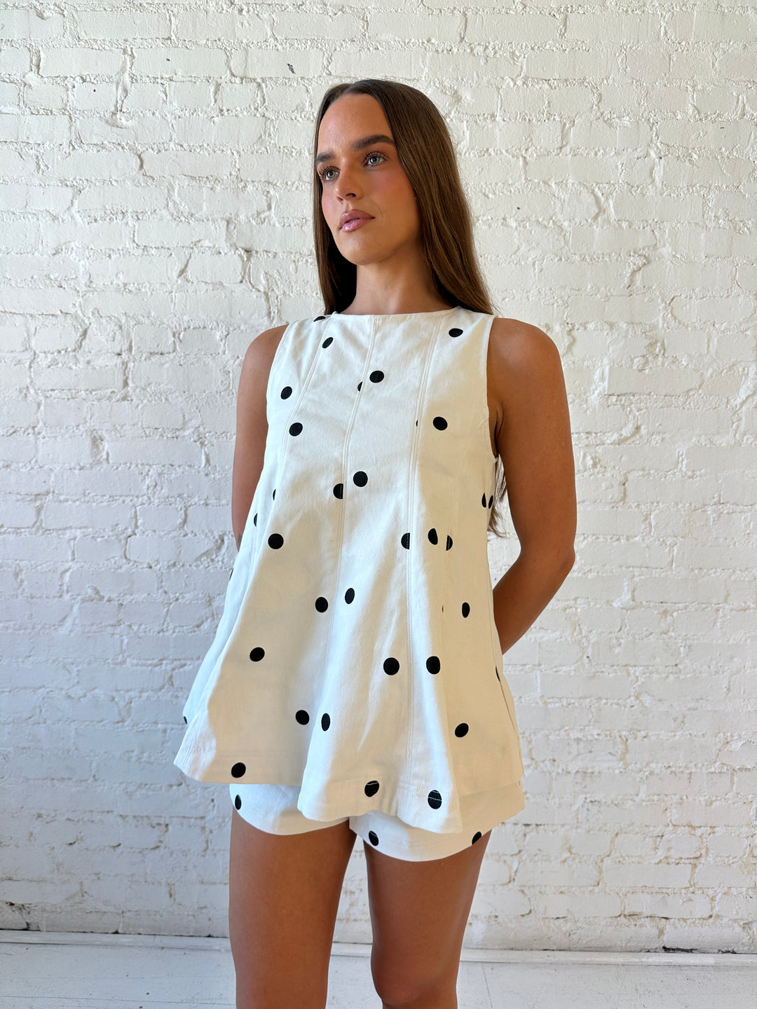 Woman wearing ivory polka dot set with black kitten heels.