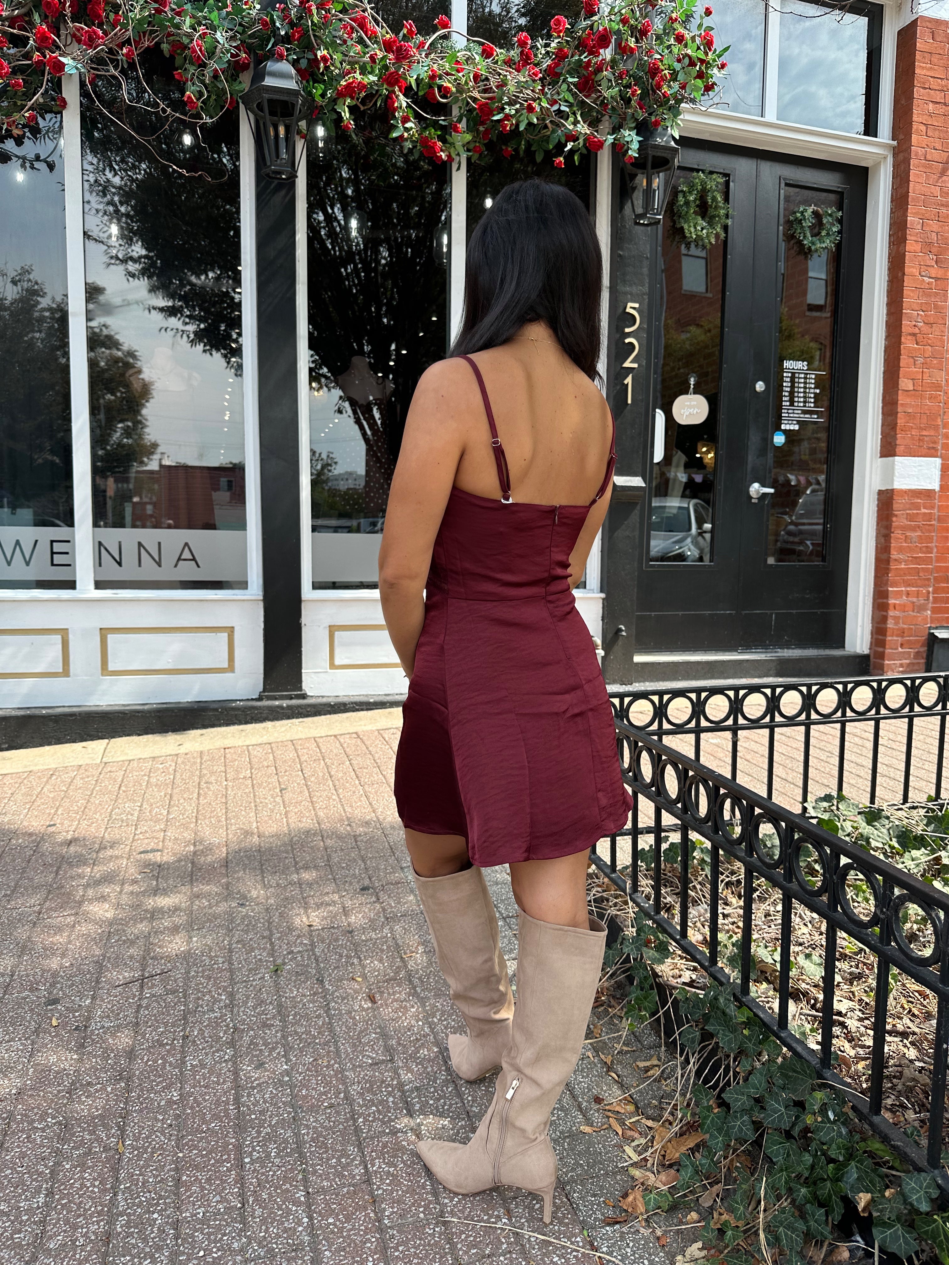 Woman wearing burgundy satin slip mini dress with lace detailing and adjustable straps.