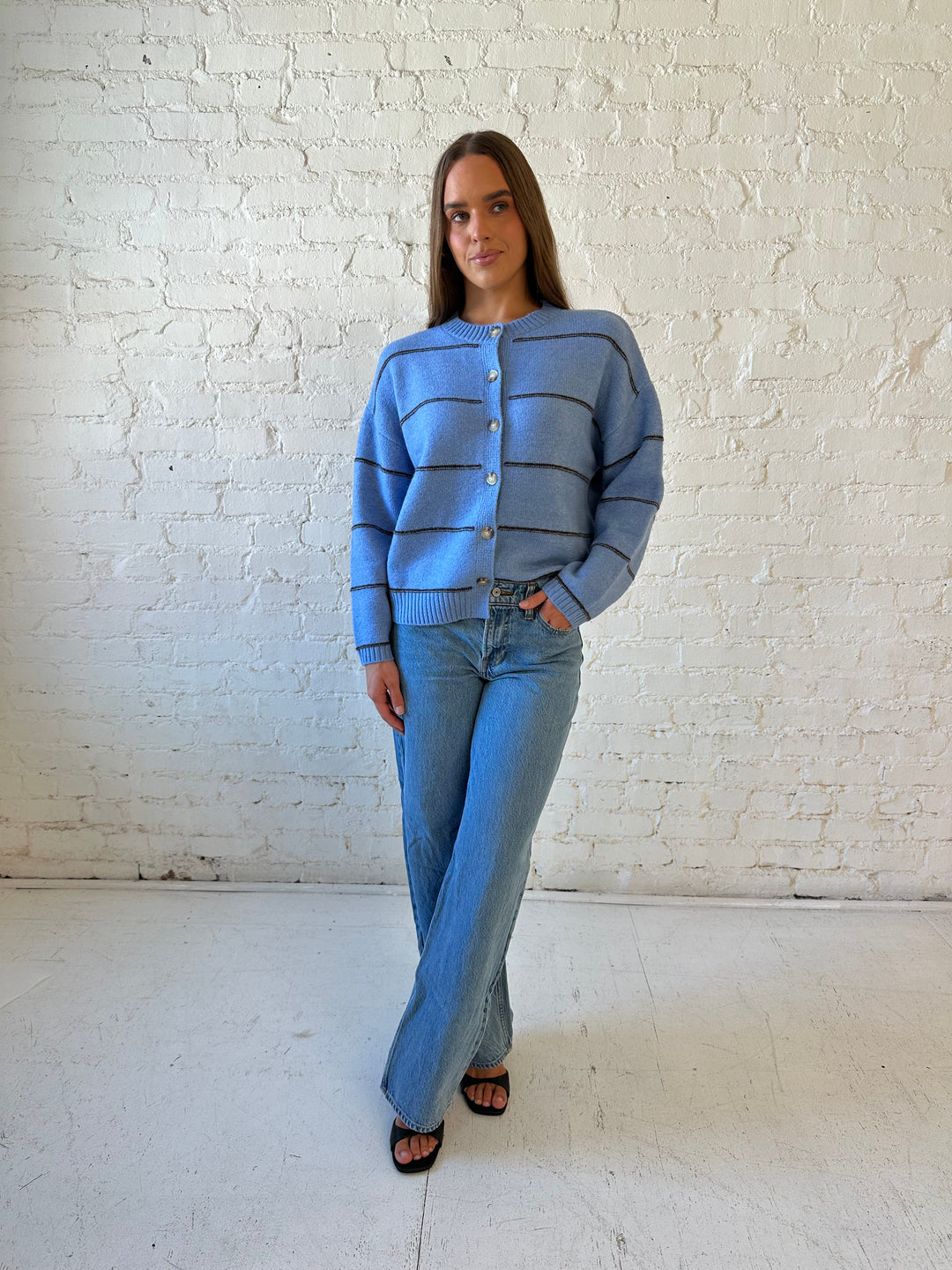 Woman wearing dusty blue striped button down cardigan with medium wash jean. 