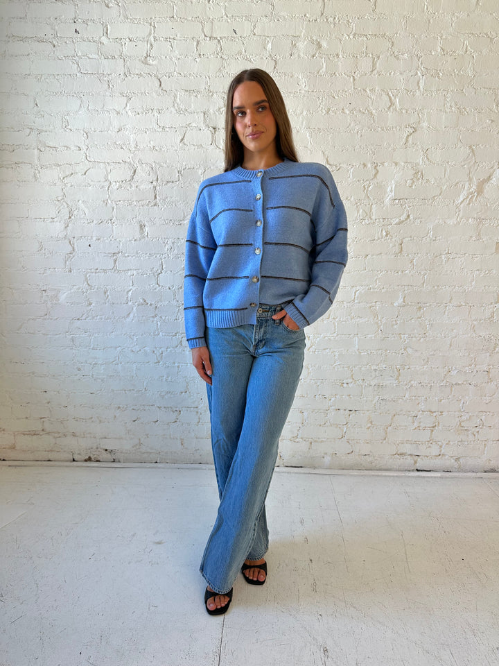 Woman wearing dusty blue striped button down cardigan with medium wash jean. 