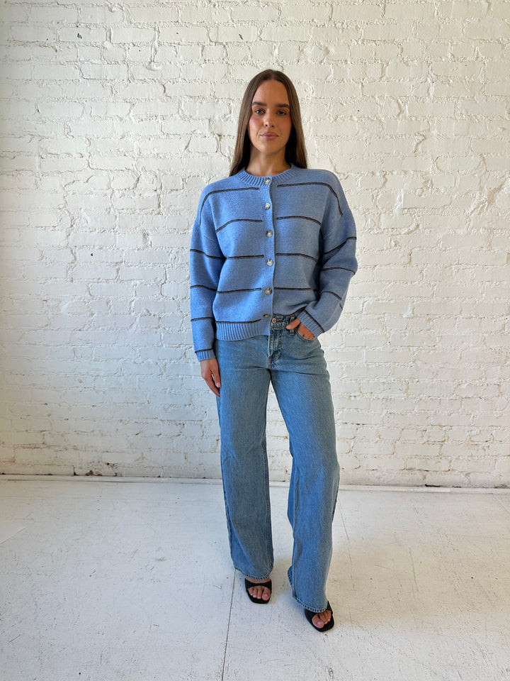 Woman wearing dusty blue striped button down cardigan with medium wash jean. 