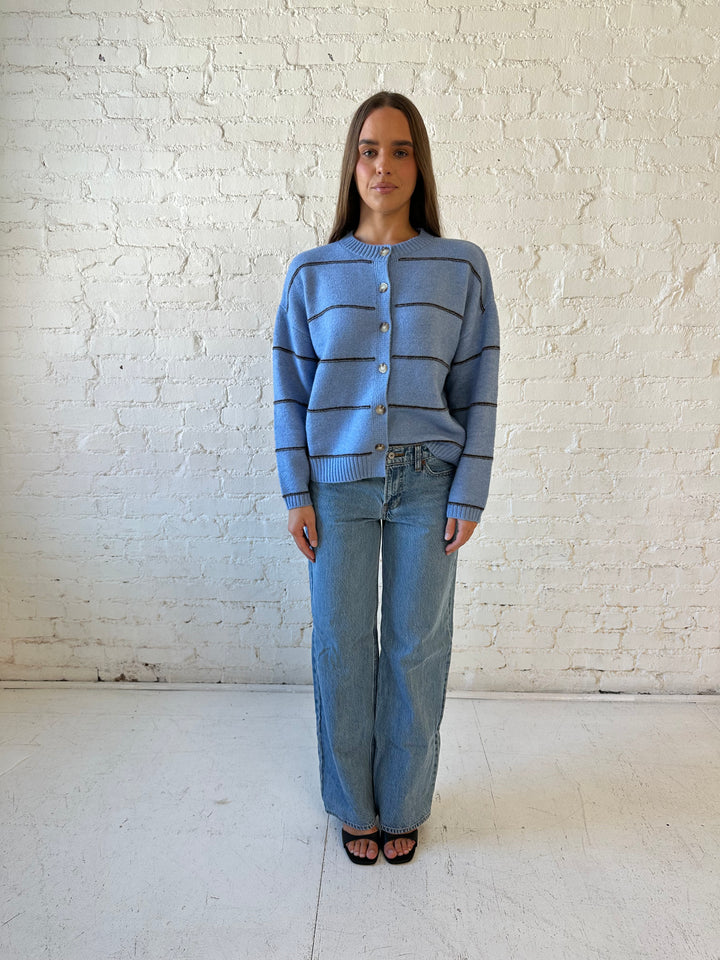 Woman wearing dusty blue striped button down cardigan with medium wash jean. 