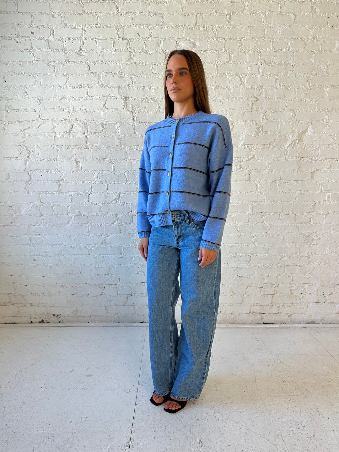 Woman wearing dusty blue striped button down cardigan with medium wash jean. 