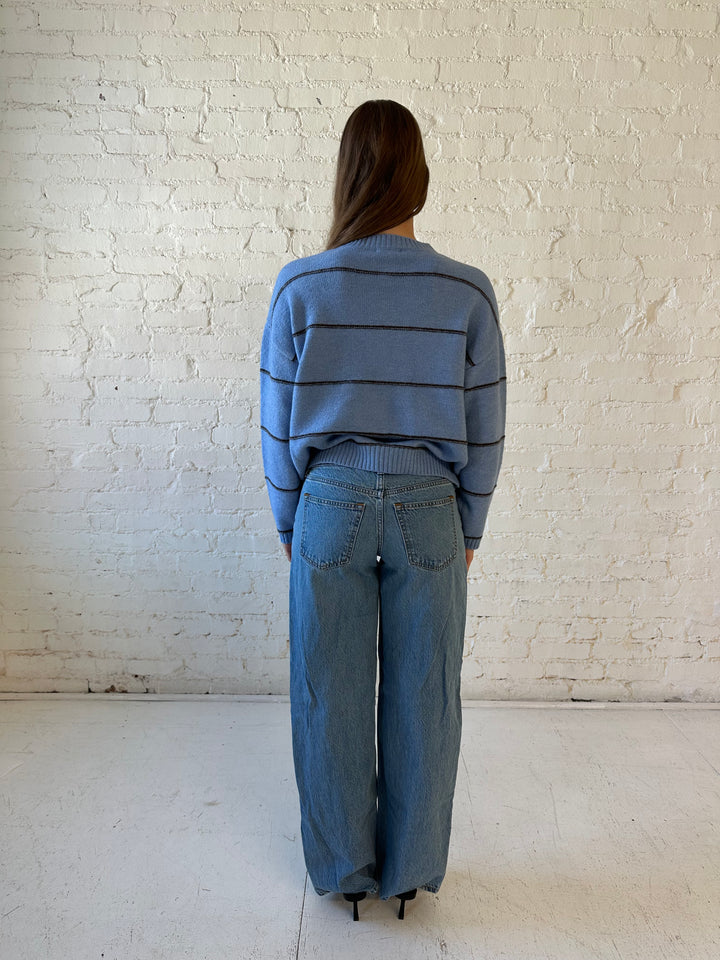 Woman wearing dusty blue striped button down cardigan with medium wash jean. 