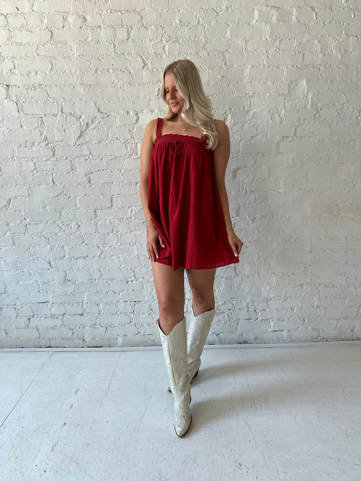 Woman wearing red shift mini dress with textured trim detail.