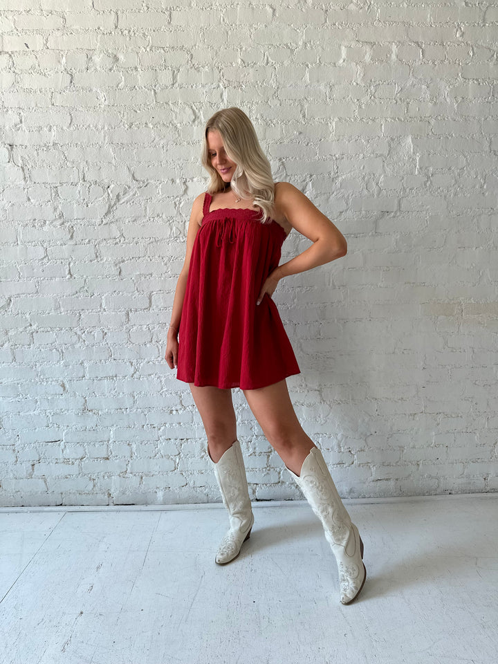 Woman wearing red shift mini dress with textured trim detail.